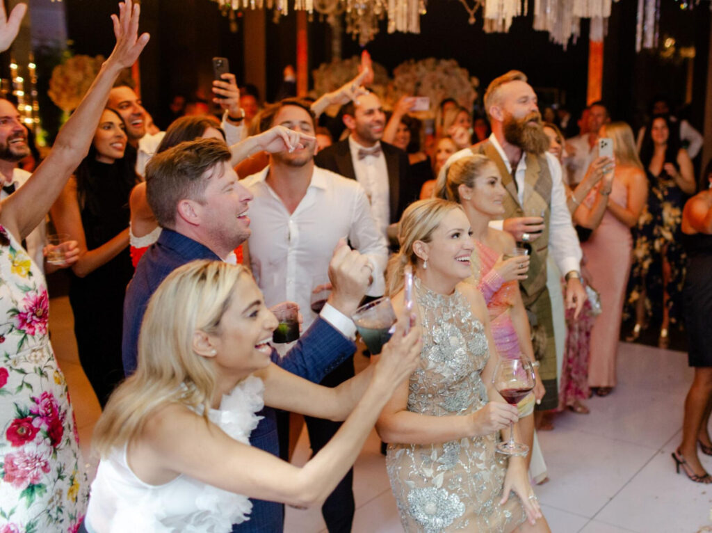 Wedding reception guests cheer on the newlywed couple