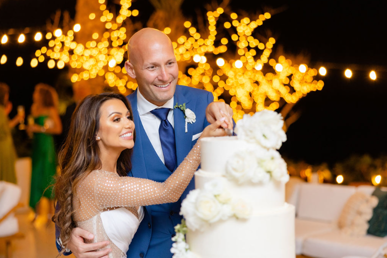 A newly married couple is cutting a cake at their luxury wedding