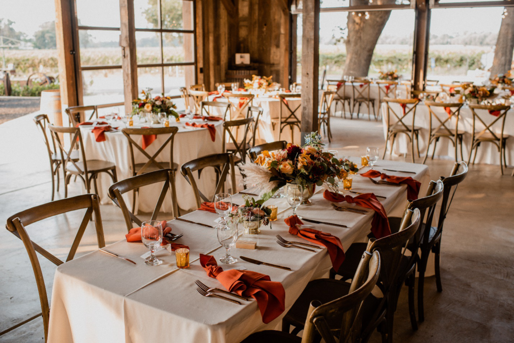 A hall with several tables set for a luxury wedding reception dinner
