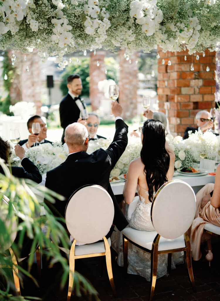 Guests raising a toast at an elegant outdoor Los Angeles wedding reception.