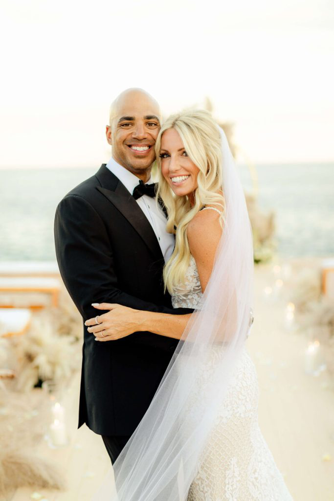 A joyful couple posing at their elegant New York wedding venue with scenic coastal views in the background.