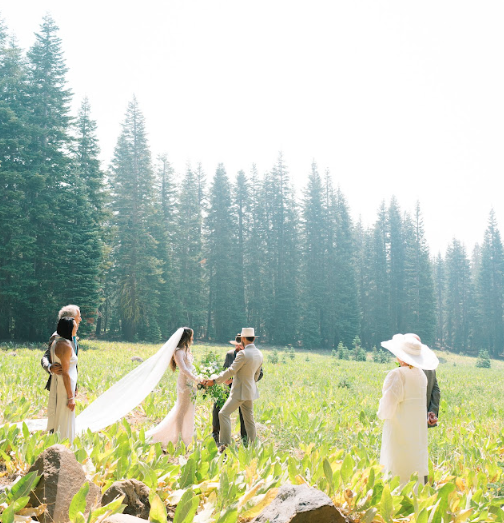 An open-air wedding ceremony set against a stunning desert landscape with golden sunlight and elegant décor