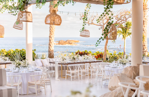 Luxurious wedding setup on a Los Cabos beach with elegant floral arrangements and ocean views.