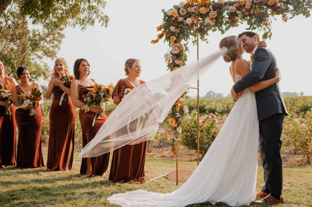 A wedding ceremony with bridesmaids in maroon dresses and formal attire.