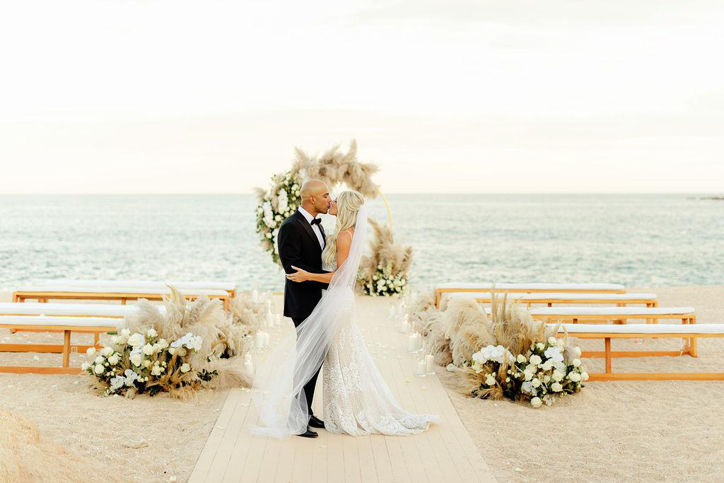 A bride and groom share a kiss at their wedding in Los Cabos.