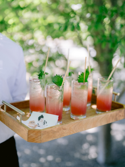 Signature cocktails served on a wooden tray at a luxury outdoor wedding