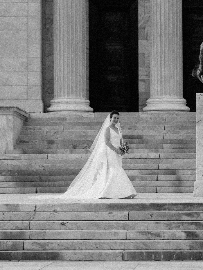 a bride standing on the stairs with historic architecture in Philadelphia.