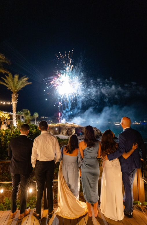 Guests enjoy a fireworks display over the ocean during a Hawaii destination wedding celebration