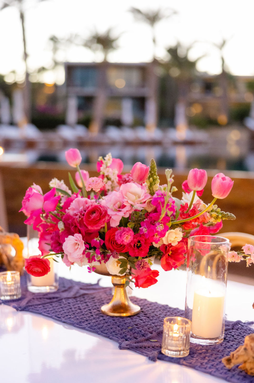 Vibrant pink and red floral centerpiece with tulips and candles on a wedding reception table in Miami