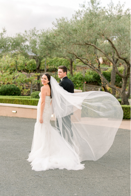 a bride and groom standing outdoors.