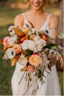 An image of a bride holding a bouquet of peach, white, and pink flowers