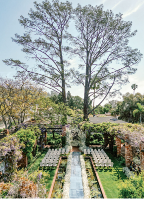 Elegant wedding reception table in Los Angeles with cascading white floral arrangements and brick pillars in the background