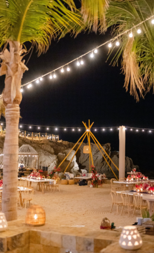 Beachside wedding reception in Miami set under string lights with tables and lounge seating in the sand