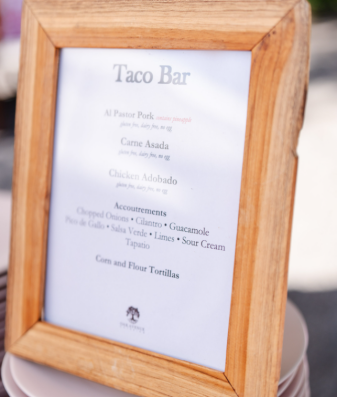 Wooden-framed sign displaying wedding taco bar menu and options.