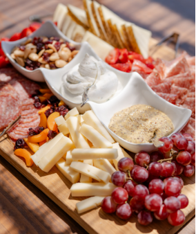 Close-up of a charcuterie board with meats, cheeses, fruits, and dips.