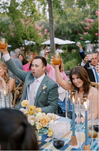 Bride and groom raising glasses with guests in a lively wedding toast.