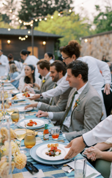 Guests being served elegant plated meals during an outdoor wedding dinner