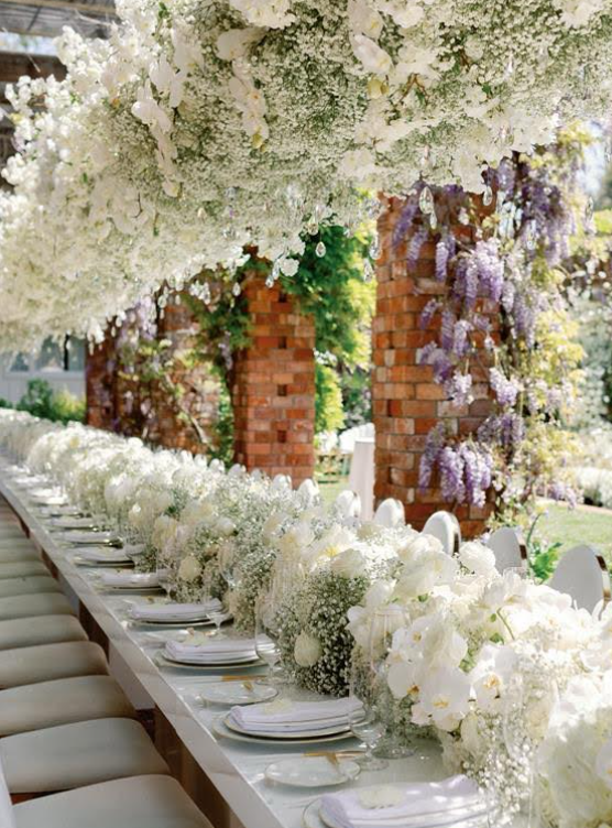 Outdoor wedding ceremony setup with white chairs and a floral aisle under tall trees in Los Angeles
