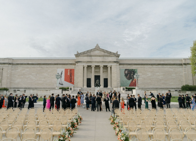 Guests gather outside a historic Washington, DC landmark for an elegant wedding ceremony with floral aisle decor.