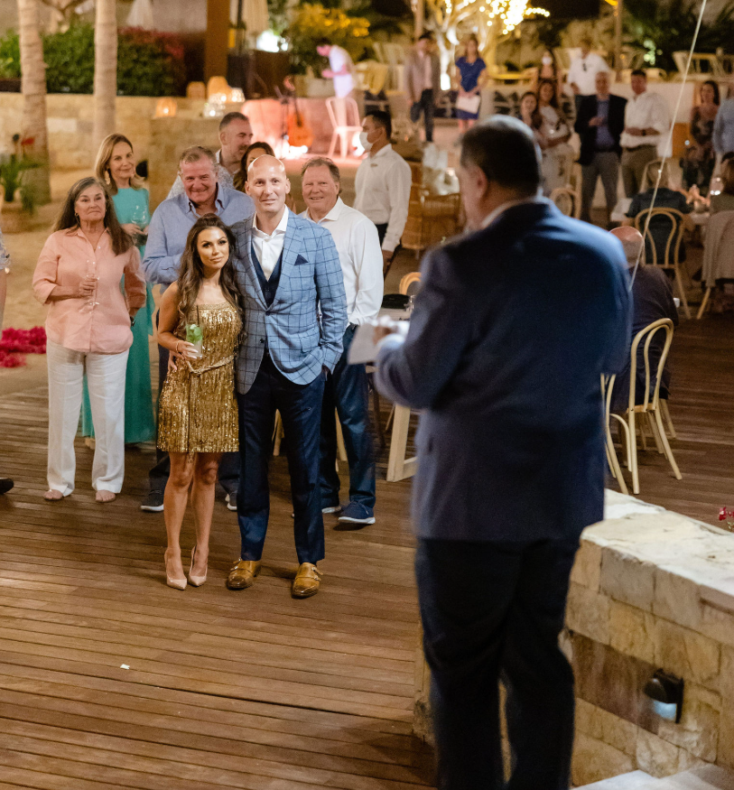 Wedding guests gather outdoors in Hawaii as a toast is given during the evening reception
