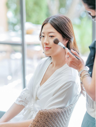 a bride in a white robe getting her makeup done