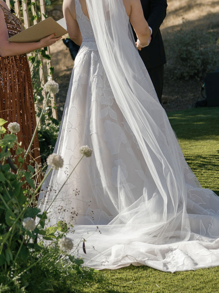 a bride in a white dress standing outdoors.