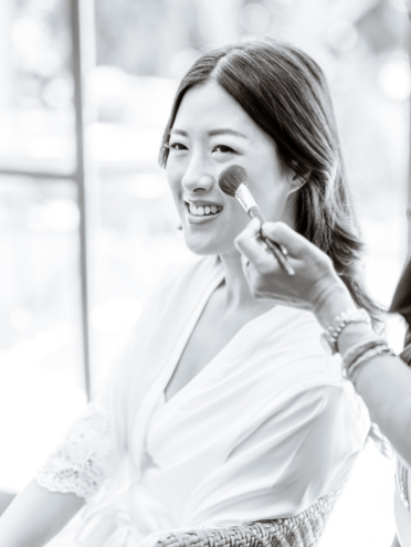 A B&W picture of a bride getting her makeup done
