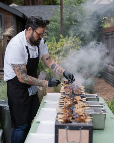 A chef preparing skewers at a wedding food station.