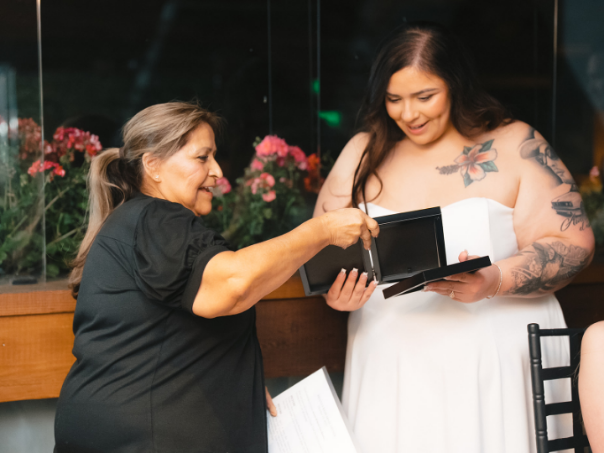 A person showing the bride some framed pictures