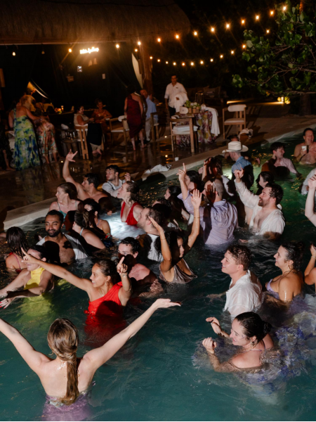 Wedding guests jump into a pool at a party