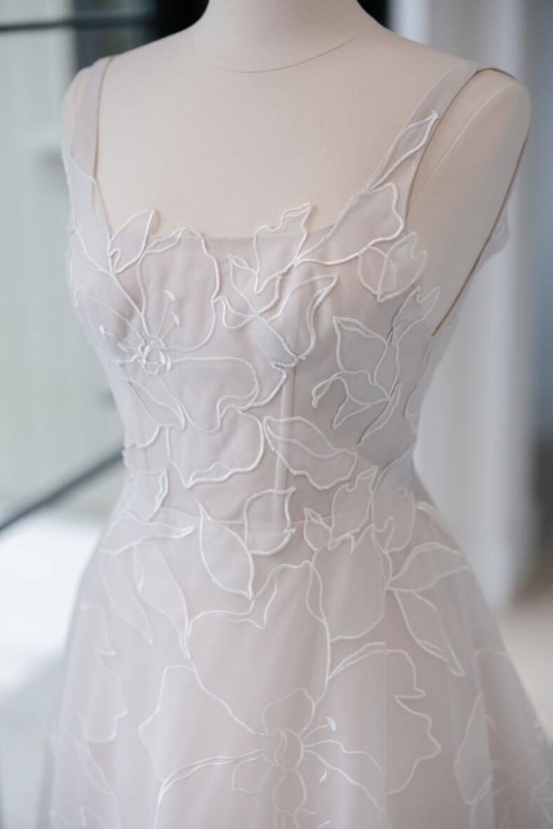 Close-up view of the intricate floral detailing on a white on white wedding gown.