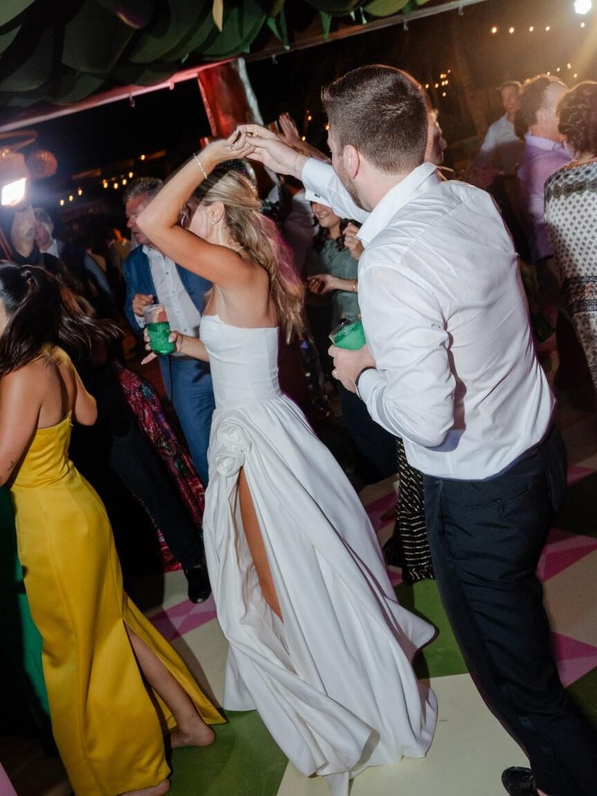 A bride and groom dancing joyously amidst wedding guests on a crowded dance floor.