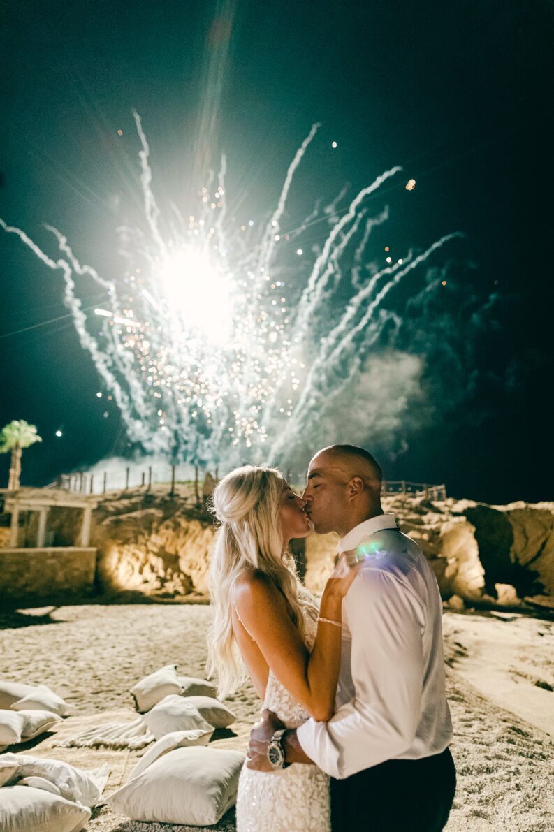 beautiful fireworks in the sky behind a couple.