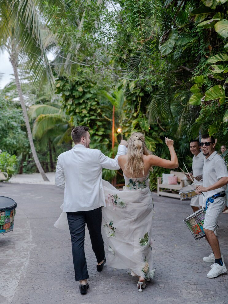 A couple entering their wedding celebration in Mexico, dancing between a mariachi band with guests celebrating around them.