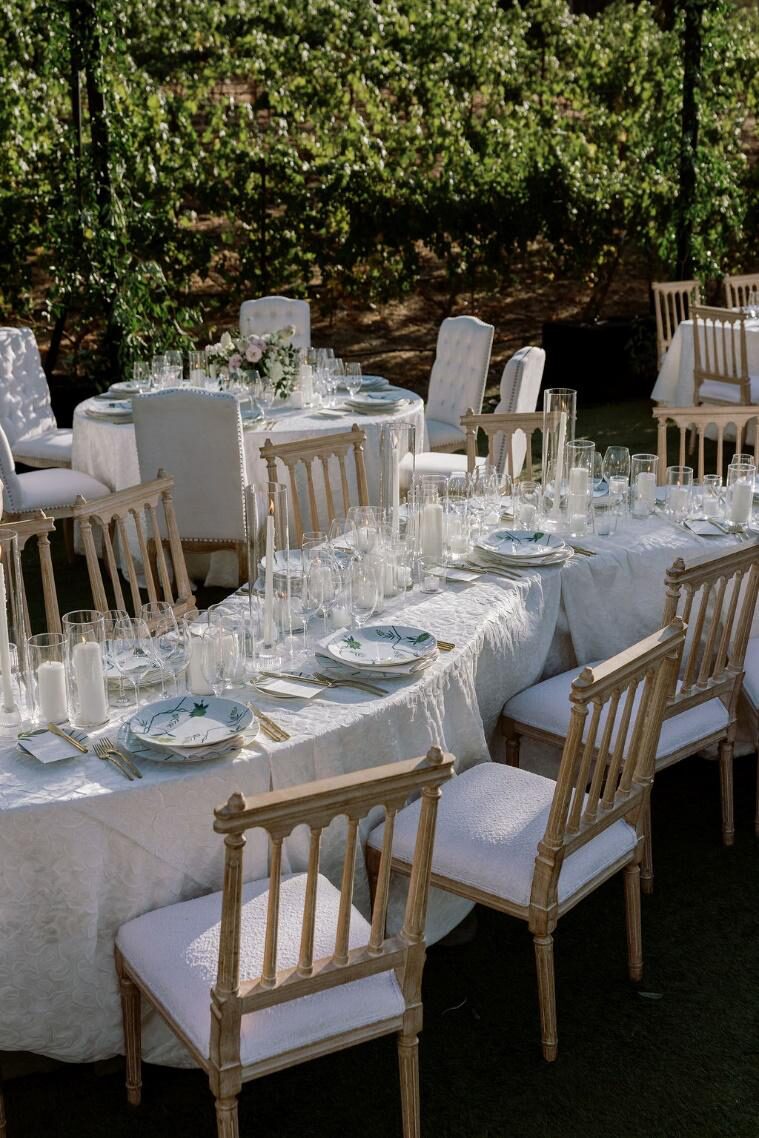 wedding tablescape with floral arrangements, gold cutlery, and multiple chairs arranged around the table for guests.