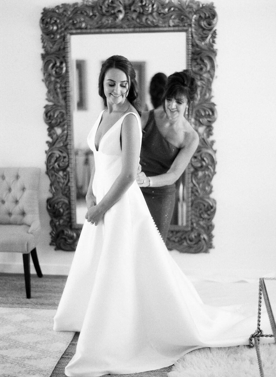 An image of a woman helping a bride with her dress