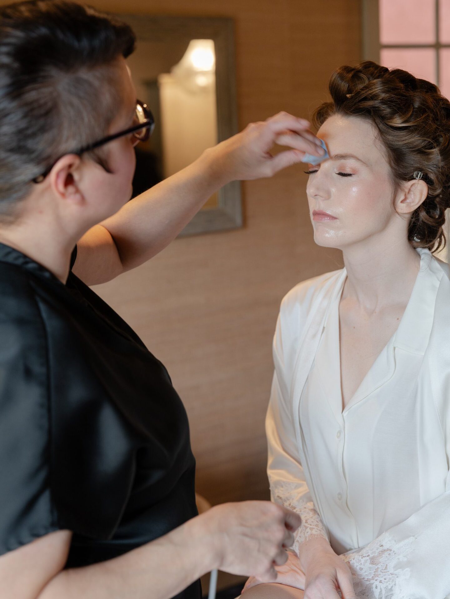 A makeup artist is applying something with a sponge on the bride’s face