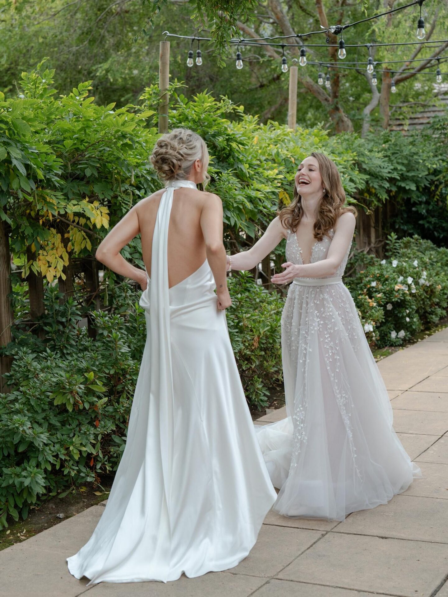 A bride in a dress admired by her bridesmaid.