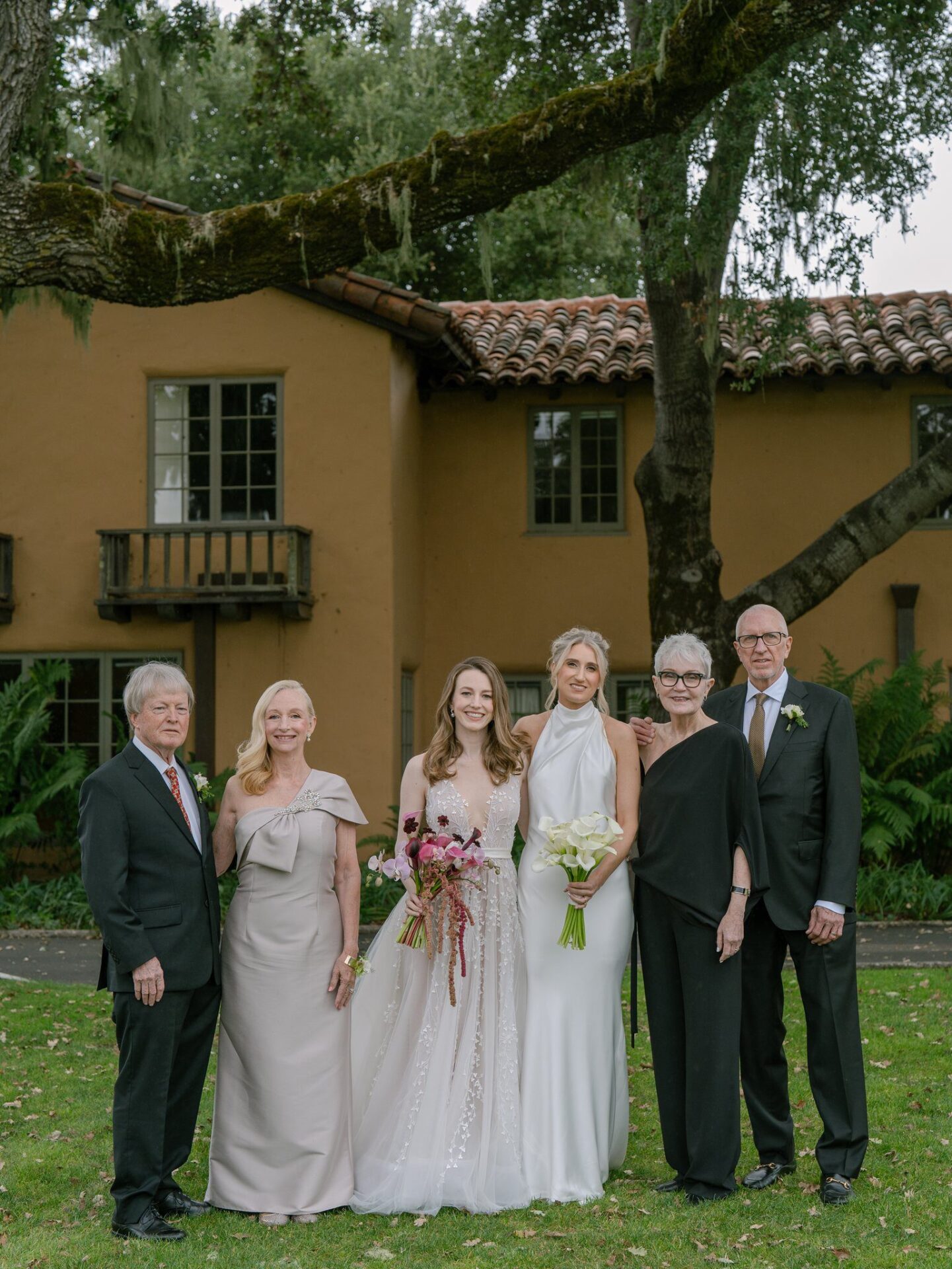 Bride and guests in stylish wedding attire, prepared for an outdoor celebration in changing weather.
