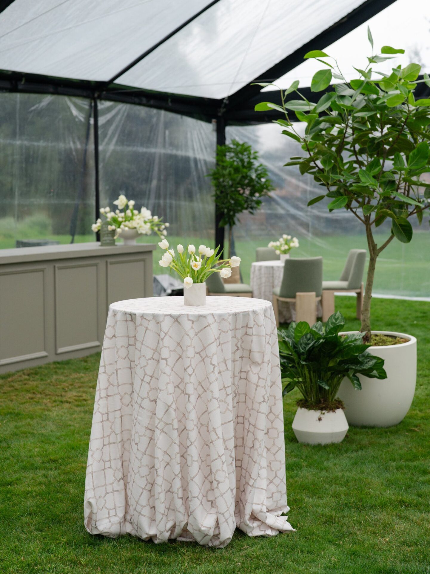Outdoor wedding setup with clear protective covering during rain